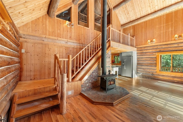 staircase with a wood stove, high vaulted ceiling, hardwood / wood-style flooring, and wood ceiling
