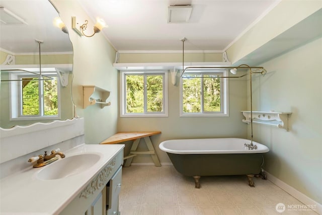 full bath featuring a freestanding bath, vanity, ornamental molding, and tile patterned floors