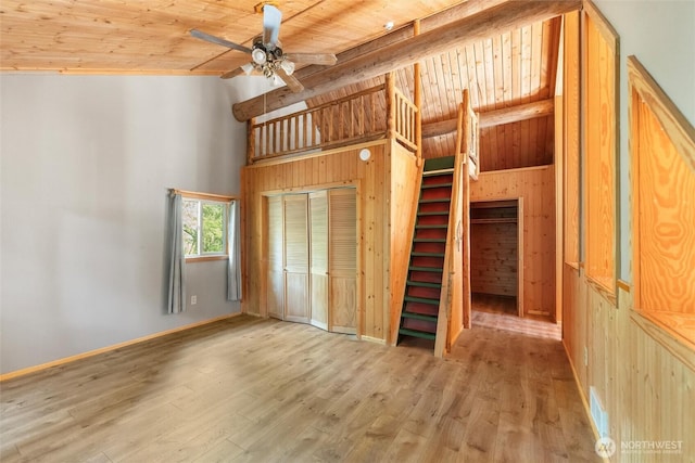 unfurnished bedroom featuring wood ceiling, wood finished floors, high vaulted ceiling, and wooden walls