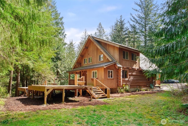 rear view of house with log siding, a yard, and a wooden deck