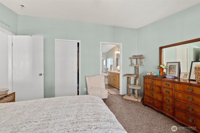 carpeted bedroom with ensuite bath and visible vents