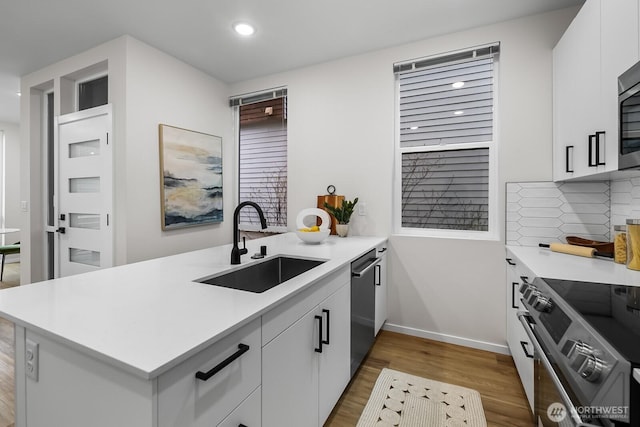 kitchen featuring light countertops, a peninsula, a sink, and stainless steel appliances