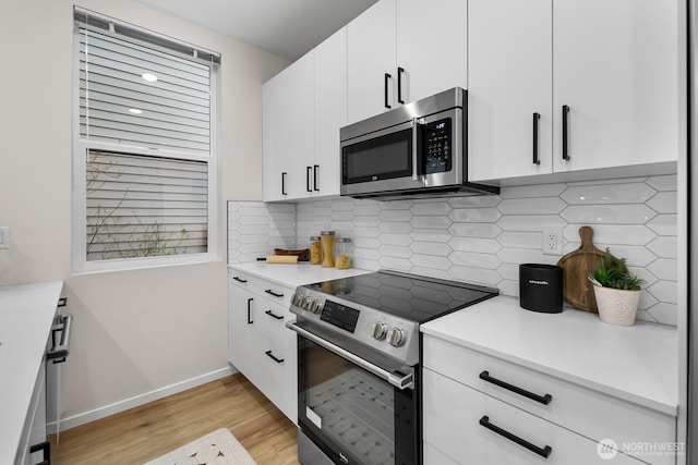 kitchen featuring light wood-style flooring, appliances with stainless steel finishes, decorative backsplash, and light countertops