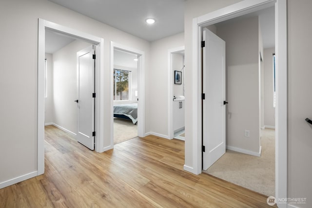 hall with light wood-style floors and baseboards
