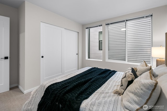 carpeted bedroom featuring a closet and baseboards