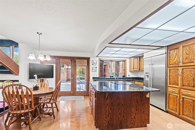 kitchen featuring french doors, light wood-type flooring, a center island, dark stone counters, and stainless steel built in refrigerator