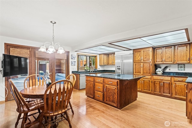 kitchen with a chandelier, stainless steel built in fridge, a kitchen island, and brown cabinets