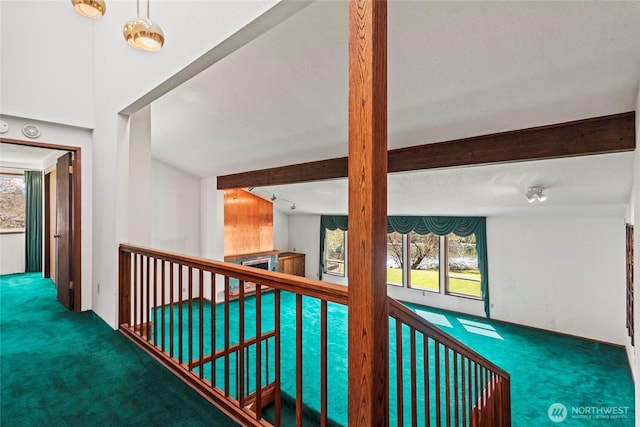 corridor featuring beamed ceiling, carpet flooring, and a healthy amount of sunlight