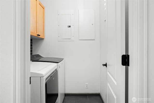 laundry room featuring independent washer and dryer, electric panel, dark tile patterned floors, baseboards, and cabinet space
