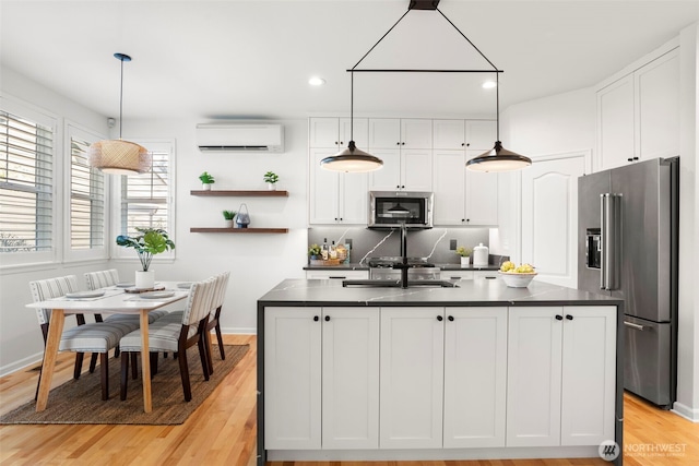 kitchen with dark countertops, white cabinets, appliances with stainless steel finishes, and a wall unit AC