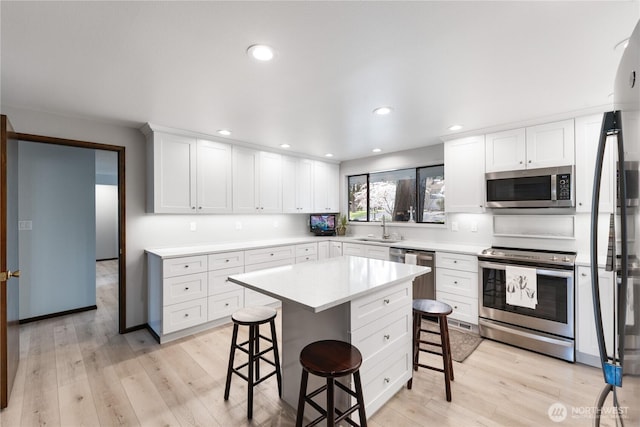 478 SW Judson Dr, Oak Harbor, WA 98277 - kitchen featuring a breakfast bar area, light wood-style floors, a sink, and appliances with stainless steel finishes