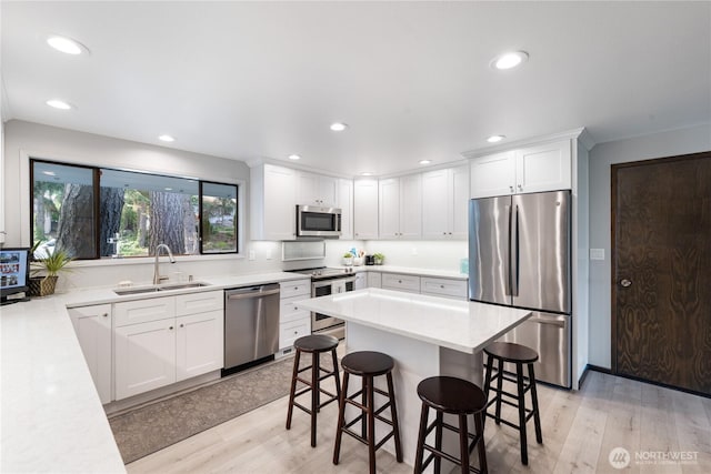 478 SW Judson Dr, Oak Harbor, WA 98277 - kitchen featuring a kitchen bar, appliances with stainless steel finishes, a sink, light countertops, and light wood finished floors