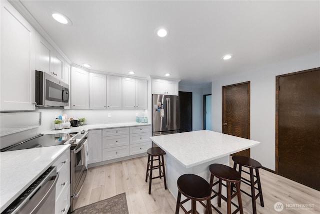 478 SW Judson Dr, Oak Harbor, WA 98277 - kitchen featuring a kitchen breakfast bar, light countertops, white cabinetry, light wood-style floors, and stainless steel appliances