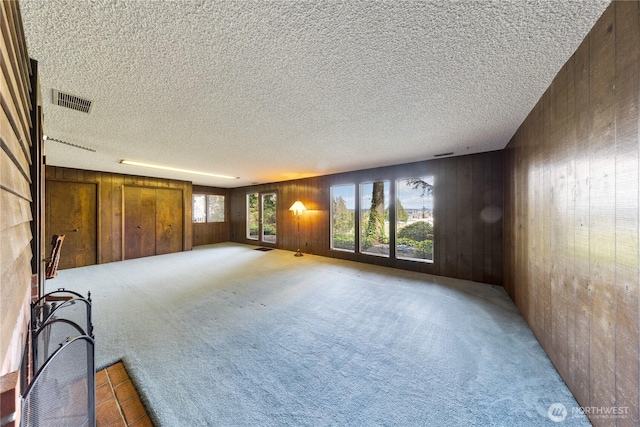 478 SW Judson Dr, Oak Harbor, WA 98277 - unfurnished living room featuring wooden walls, visible vents, light colored carpet, and a textured ceiling