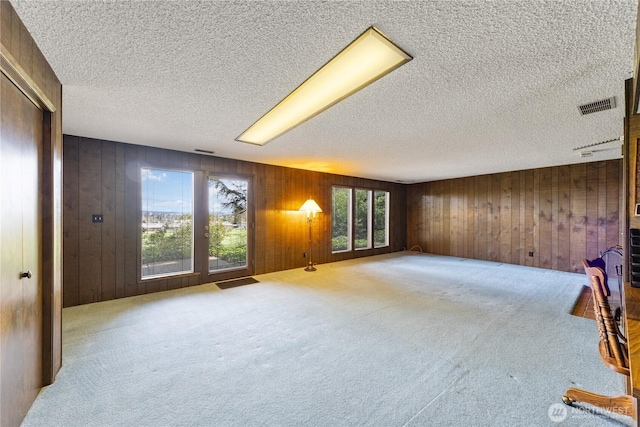 478 SW Judson Dr, Oak Harbor, WA 98277 - unfurnished living room with a textured ceiling, wood walls, visible vents, and carpet floors