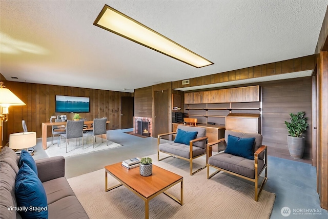 478 SW Judson Dr, Oak Harbor, WA 98277 - living area featuring wooden walls, a textured ceiling, concrete flooring, and a fireplace