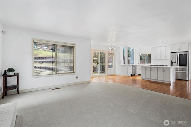 13923 SE 79th Dr, Newcastle, WA 98059 - unfurnished living room with visible vents, baseboards, a chandelier, light wood-style floors, and light carpet