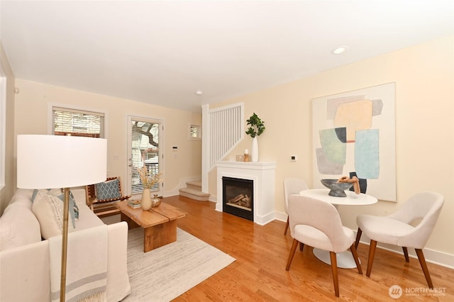 living room with light wood-style floors, baseboards, a glass covered fireplace, and recessed lighting