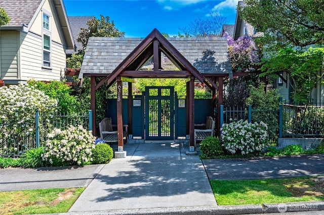 doorway to property with roof with shingles and fence