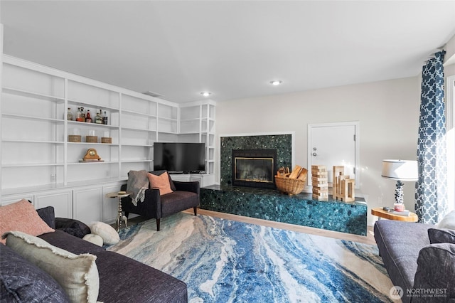 living area with recessed lighting, wood finished floors, and a premium fireplace