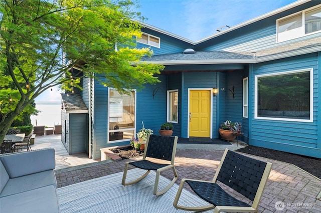 doorway to property featuring a shingled roof and a patio
