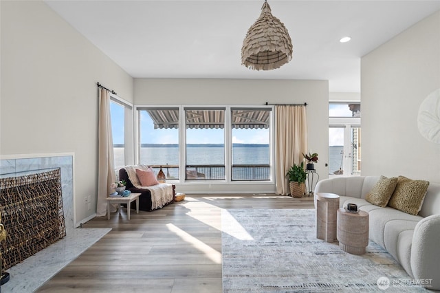 living room featuring recessed lighting, wood finished floors, a water view, and plenty of natural light