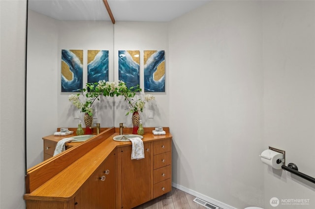 bathroom with baseboards, vanity, wood finished floors, and visible vents