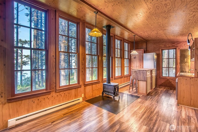 unfurnished sunroom with a wood stove, baseboard heating, a baseboard heating unit, and a sink
