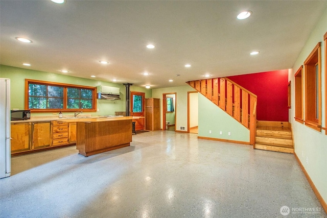 kitchen with under cabinet range hood, a kitchen island, baseboards, and recessed lighting