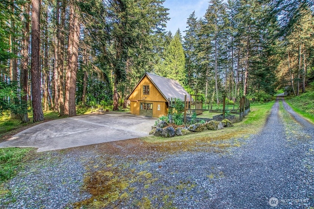 garage with driveway and a view of trees