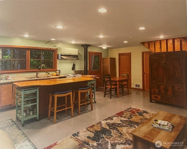bar featuring visible vents, a sink, recessed lighting, and under cabinet range hood