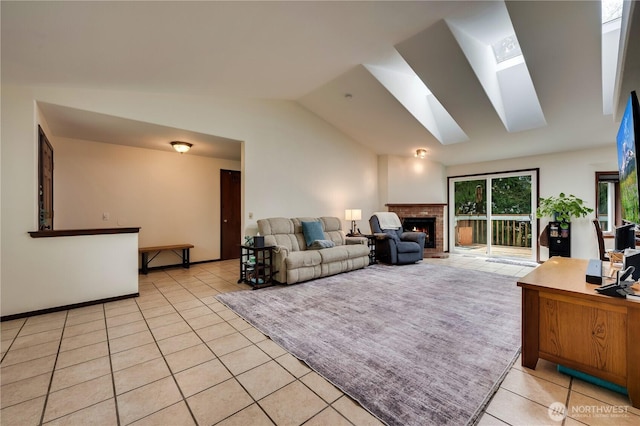 living area featuring vaulted ceiling with skylight, light tile patterned flooring, and a brick fireplace