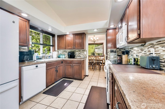 kitchen with tasteful backsplash, light tile patterned floors, a notable chandelier, a sink, and white appliances