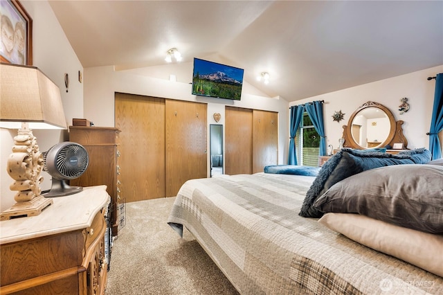 bedroom with carpet floors, multiple closets, and lofted ceiling