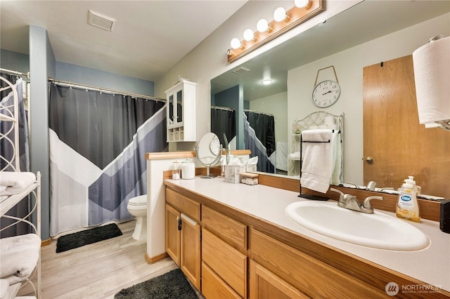 bathroom featuring visible vents, a shower with curtain, toilet, vanity, and wood finished floors
