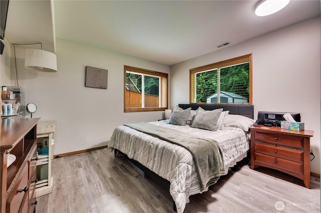 bedroom with visible vents, baseboards, and light wood finished floors