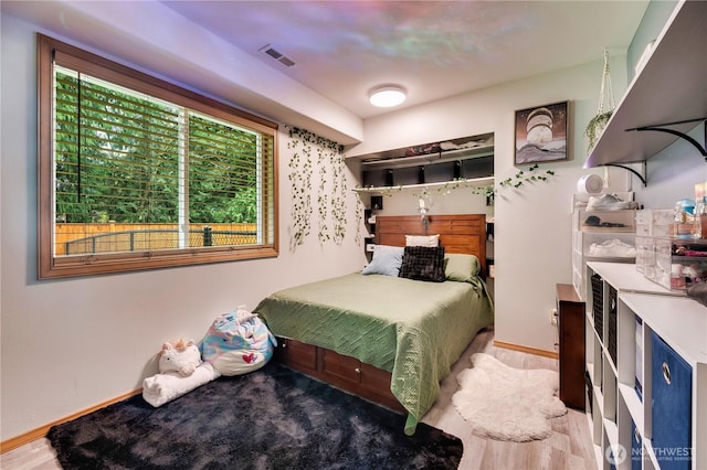bedroom featuring wood finished floors, baseboards, and visible vents
