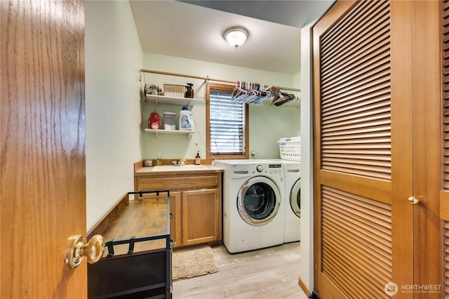 clothes washing area with cabinet space, independent washer and dryer, light wood-style floors, and a sink