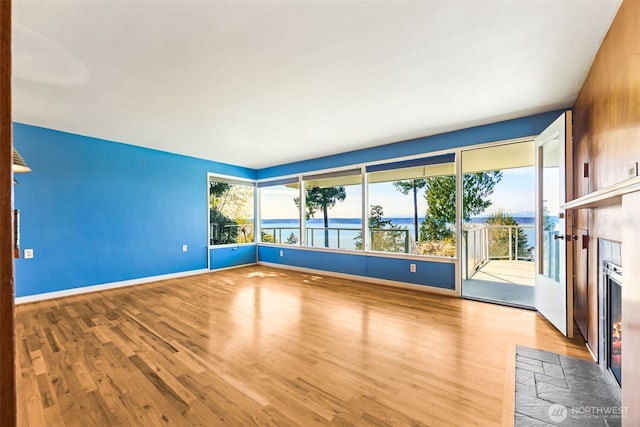 unfurnished living room with baseboards, wood finished floors, and a fireplace