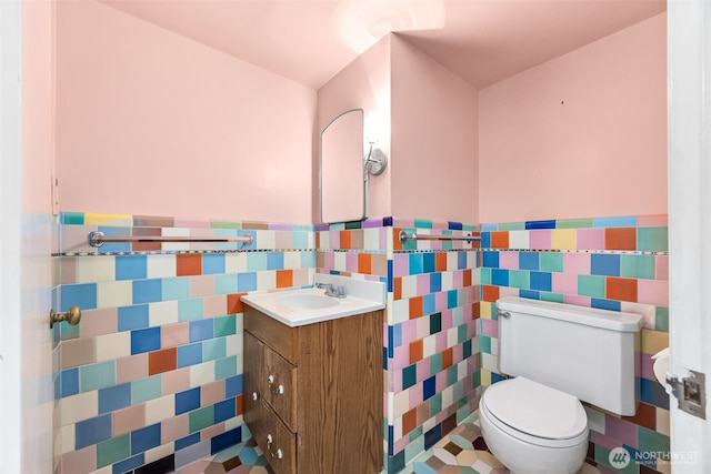 bathroom featuring a wainscoted wall, vanity, toilet, and tile walls