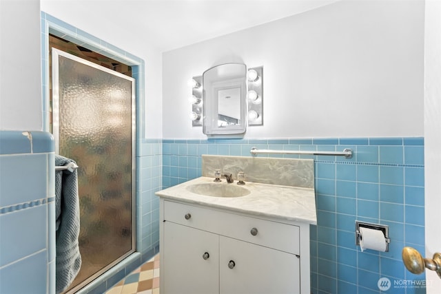 bathroom featuring vanity, tile walls, a wainscoted wall, and a stall shower