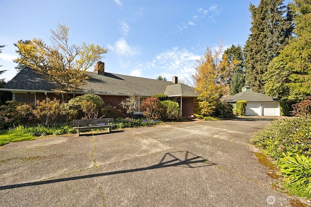 ranch-style home featuring driveway, a chimney, and a garage