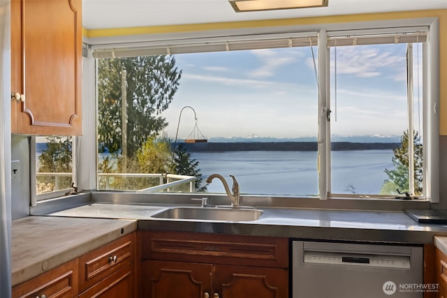 kitchen featuring a water view, brown cabinetry, a sink, and dishwasher