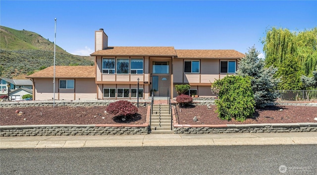 view of front of home with a chimney, fence, and a mountain view