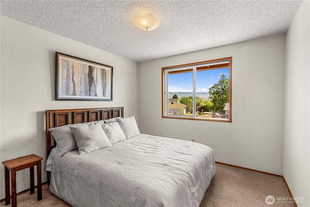 bedroom featuring carpet, baseboards, and a textured ceiling