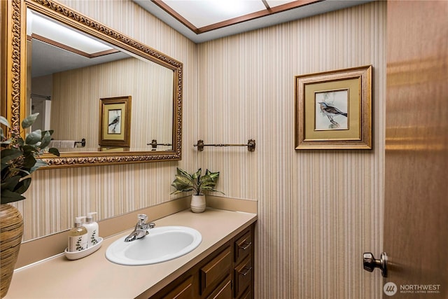 bathroom with wallpapered walls and vanity