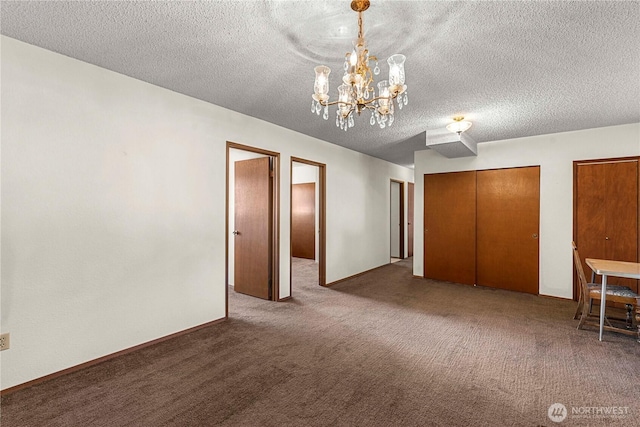 unfurnished bedroom featuring carpet, a chandelier, multiple closets, and a textured ceiling
