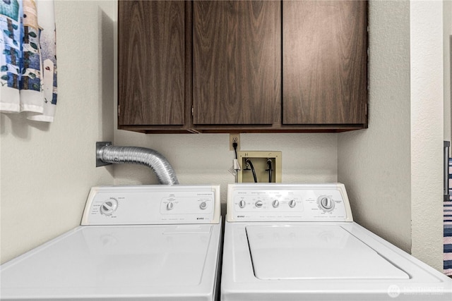 laundry room featuring cabinet space, a textured wall, and washing machine and clothes dryer