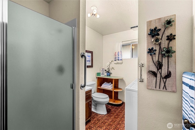 bathroom with vanity, washer / dryer, a stall shower, and toilet