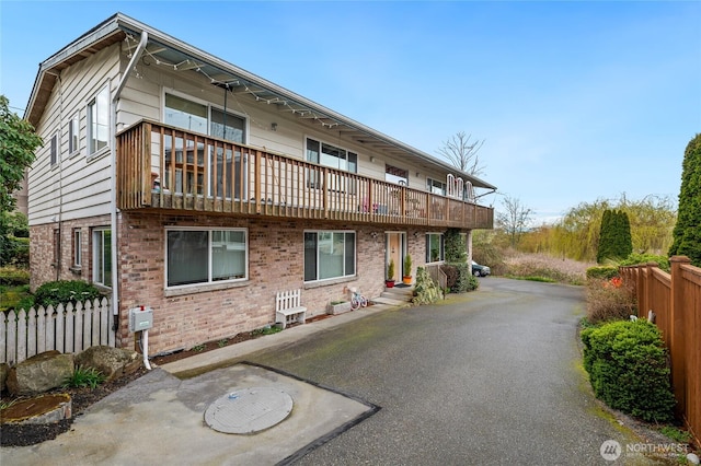 exterior space featuring brick siding, fence, and a balcony